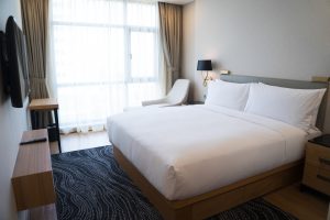 Small hotel bedroom with white walls and panoramic window